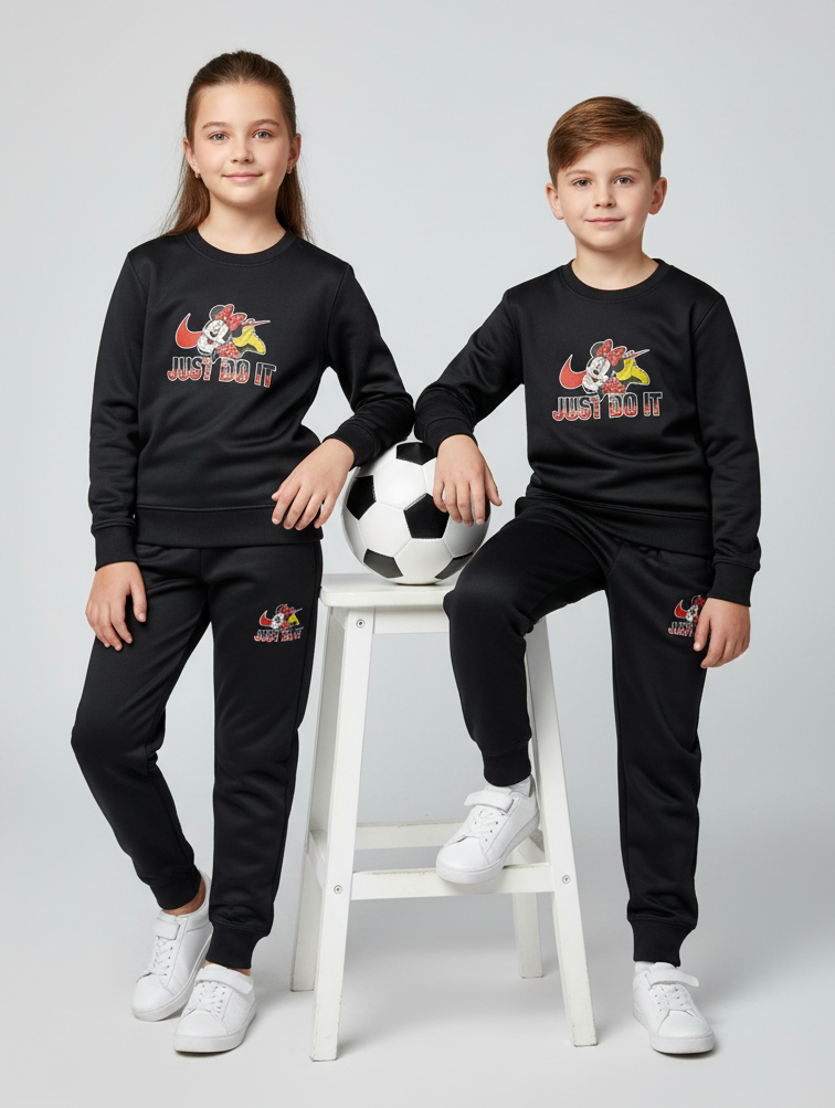 Two children wearing matching black outfits with a logo and text, sitting on a stool with a soccer ball.